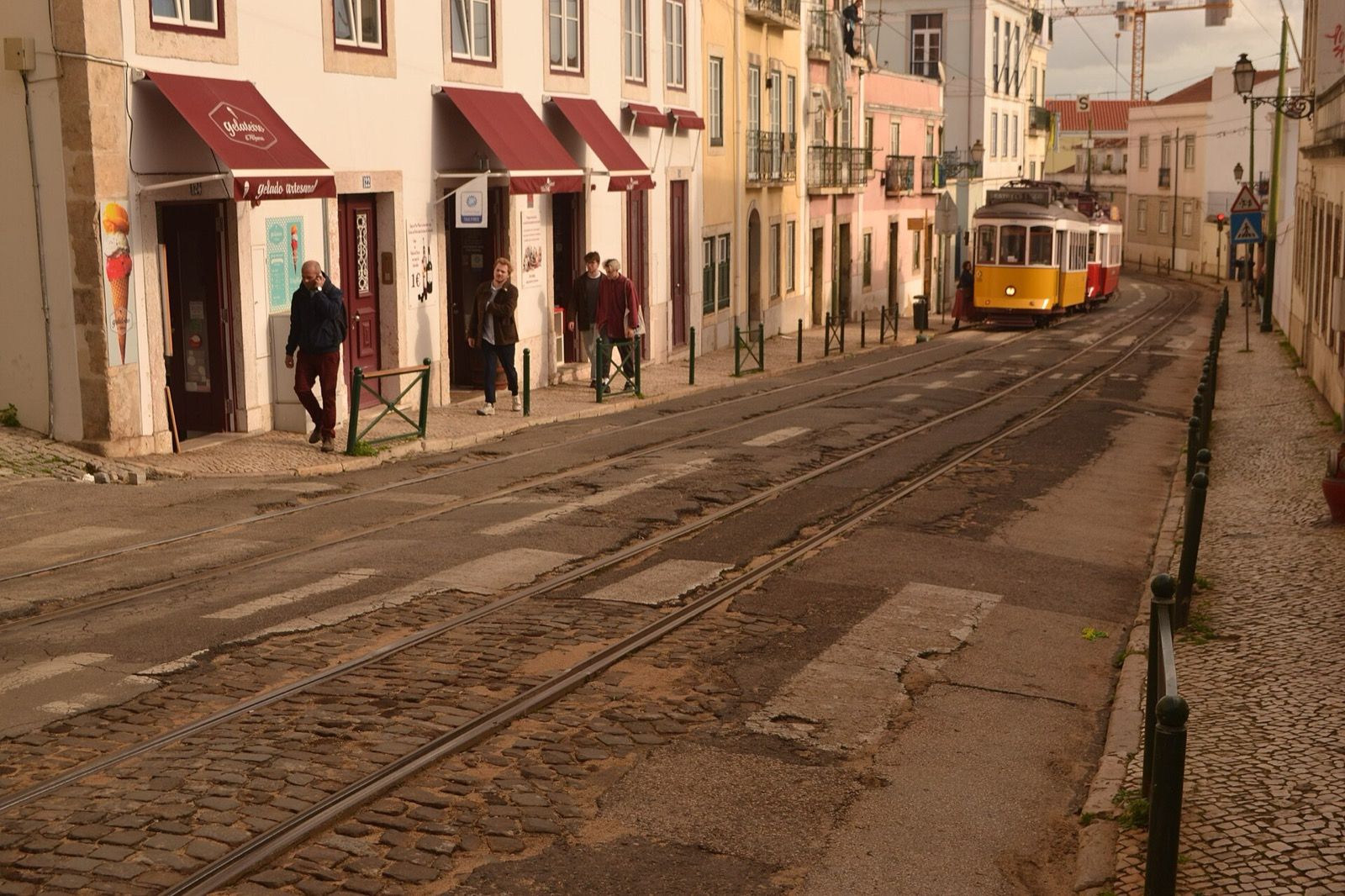 A yellow tram on a cobbled street in Alfama