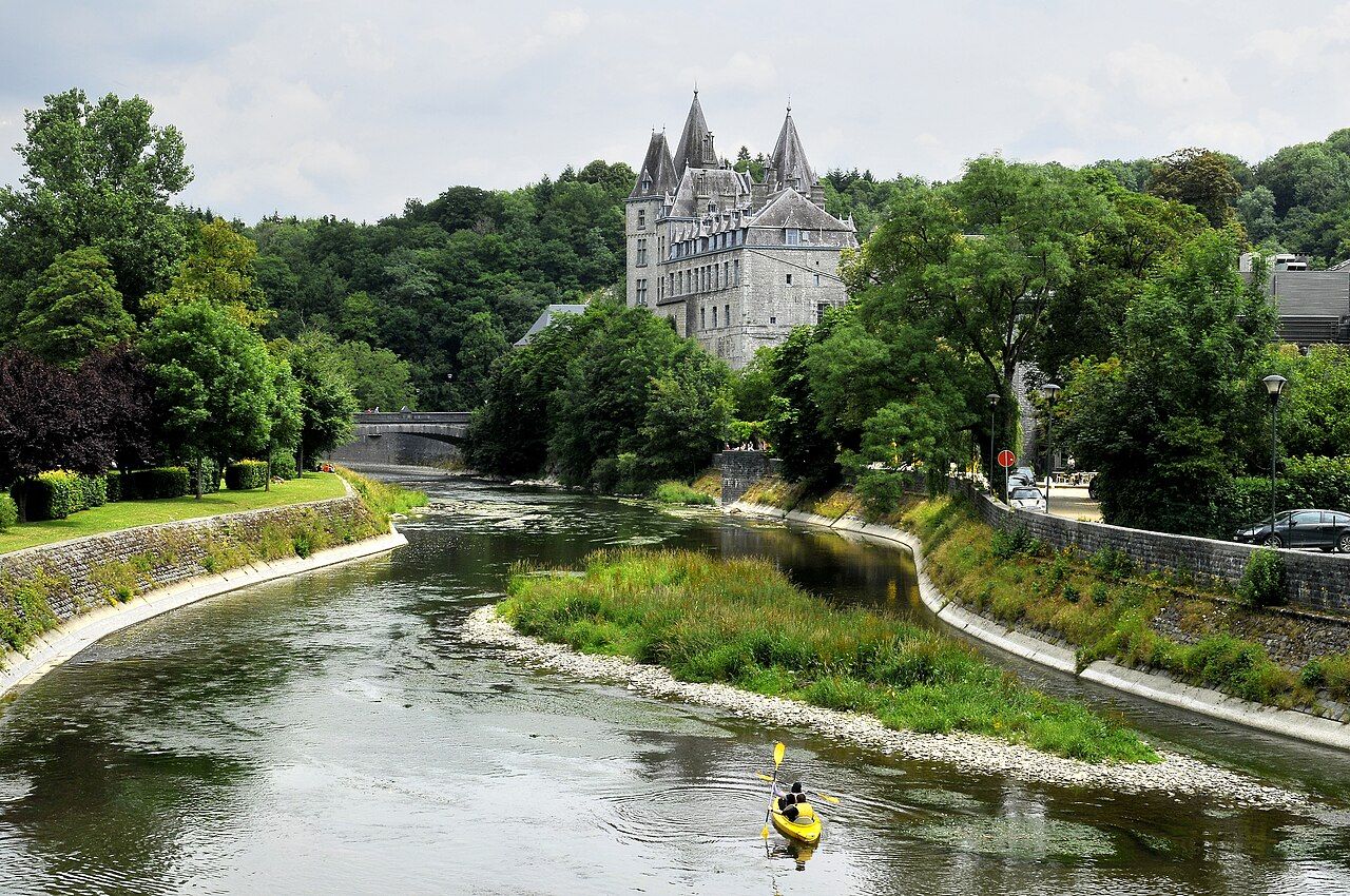 The Ourthe river running past the old stone houses and wooded hills of Durbuy in the Belgian Ardennes