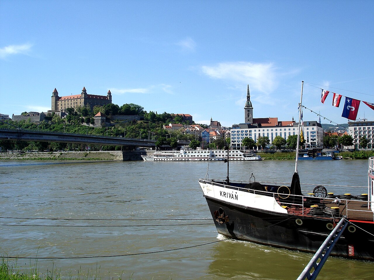 Bratislava Castle on its hill above the Danube, with river boats in the foreground