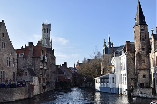The Rozenhoedkaai canal in Bruges with the Belfry tower rising behind the gabled houses