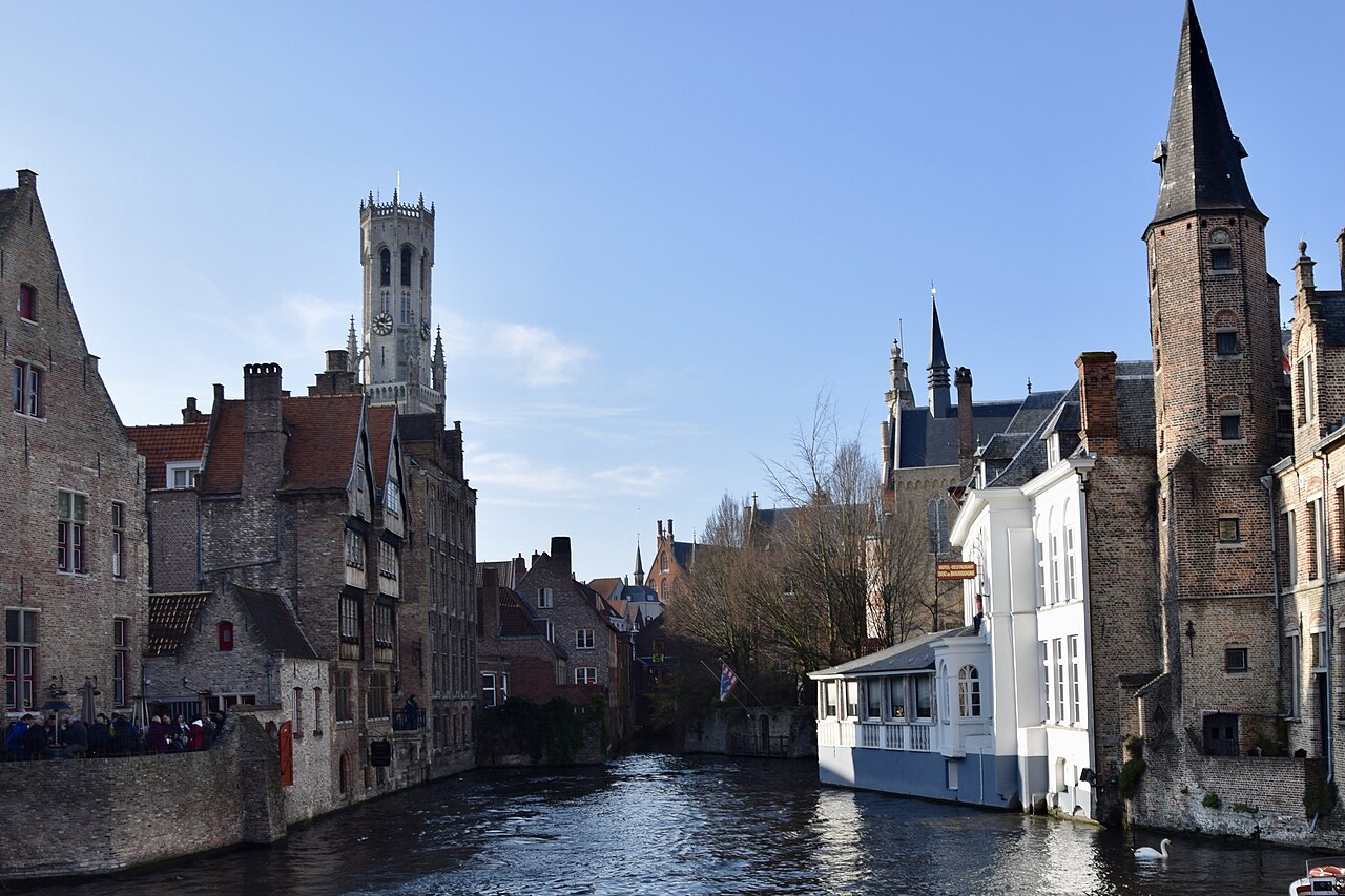 The Rozenhoedkaai canal in Bruges with the Belfry tower rising behind the gabled houses