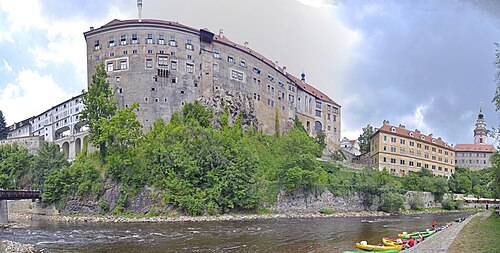 Český Krumlov castle and its tower on a rock above a bend of the Vltava river, with the old town roofs below
