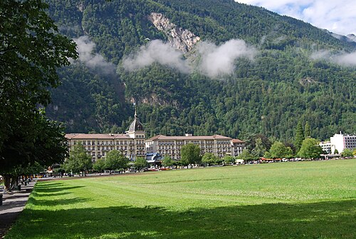 The Höhematte meadow in Interlaken with the Victoria-Jungfrau hotel and a wooded mountainside behind
