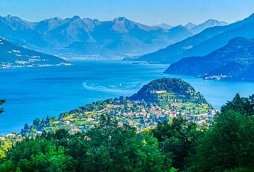 The wooded Bellagio promontory with red-roofed houses, blue lake water and mountains behind
