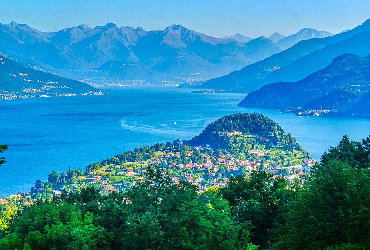 The wooded Bellagio promontory with red-roofed houses, blue lake water and mountains behind