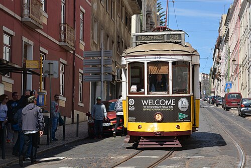 A yellow tram climbing a narrow street in Alfama, Lisbon