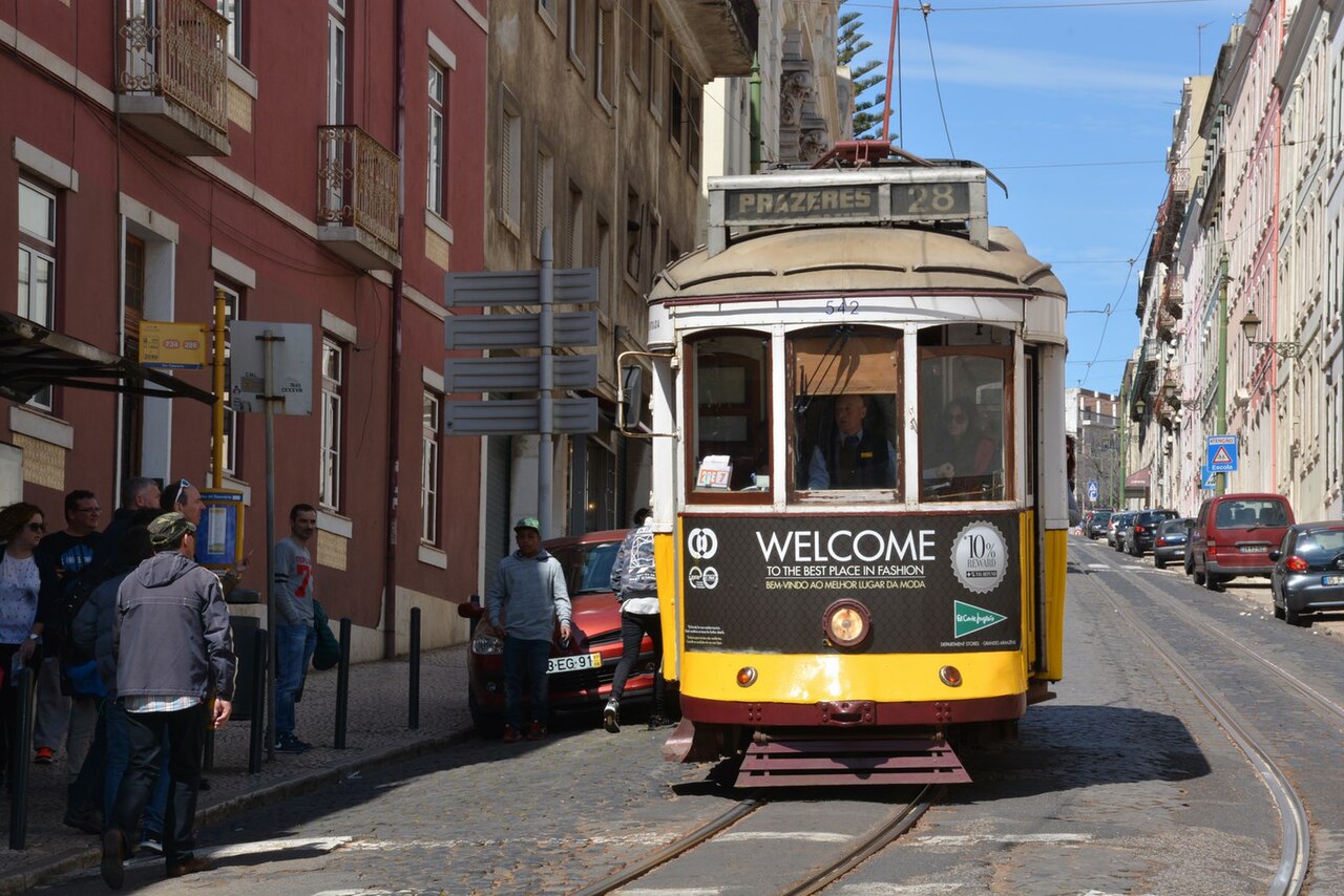 A yellow tram climbing a narrow street in Alfama, Lisbon