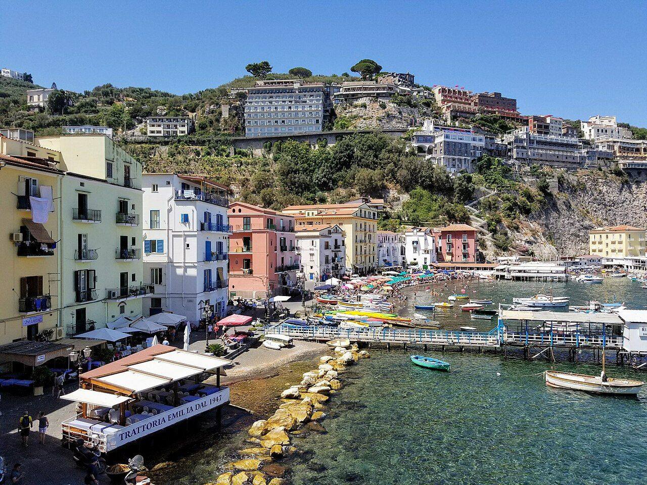 The harbor of Marina Grande in Sorrento, with pastel houses, small boats and the town on the cliff above