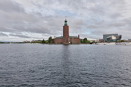 Stockholm City Hall, a red brick building with a tall tower, seen across the water from Riddarholmen