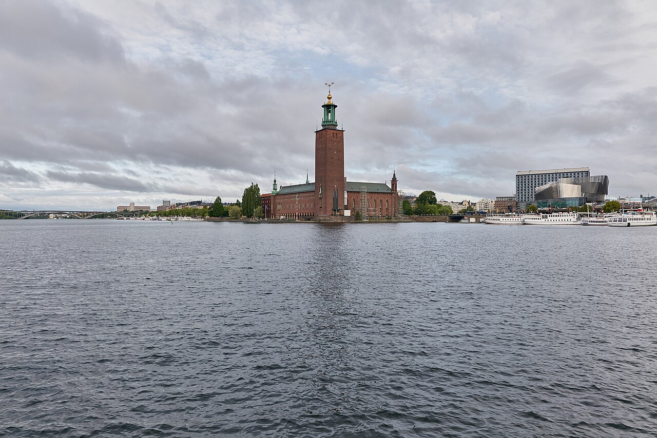 Stockholm City Hall, a red brick building with a tall tower, seen across the water from Riddarholmen
