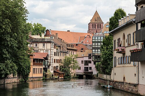 A canal in Petite France, Strasbourg, with half-timbered houses along the water and a stone tower behind