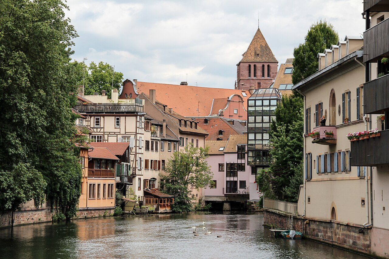 A canal in Petite France, Strasbourg, with half-timbered houses along the water and a stone tower behind